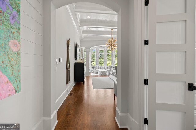 hall with arched walkways, an inviting chandelier, dark wood-type flooring, beamed ceiling, and baseboards