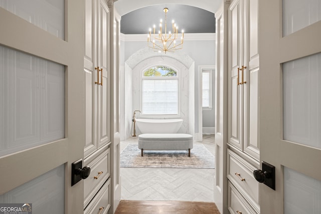 interior space featuring parquet floors, lofted ceiling, ornamental molding, and a chandelier