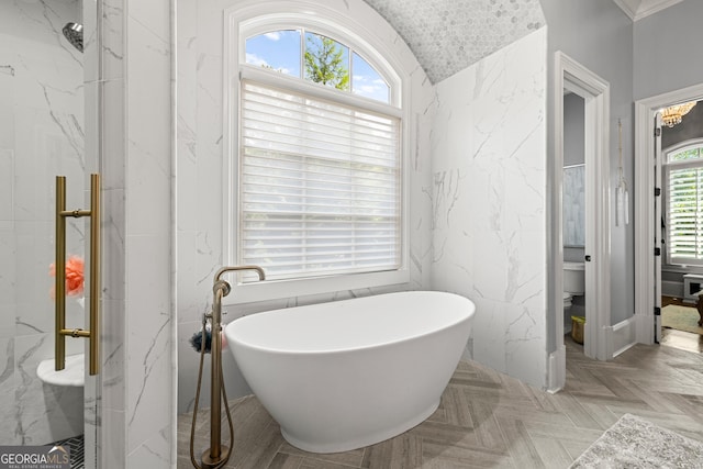 bathroom featuring toilet, a freestanding tub, and a marble finish shower