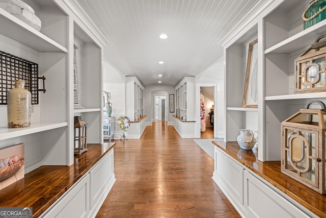 corridor featuring baseboards, arched walkways, wooden ceiling, wood finished floors, and recessed lighting