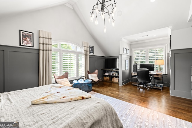 bedroom with high vaulted ceiling, multiple windows, a decorative wall, and wood finished floors