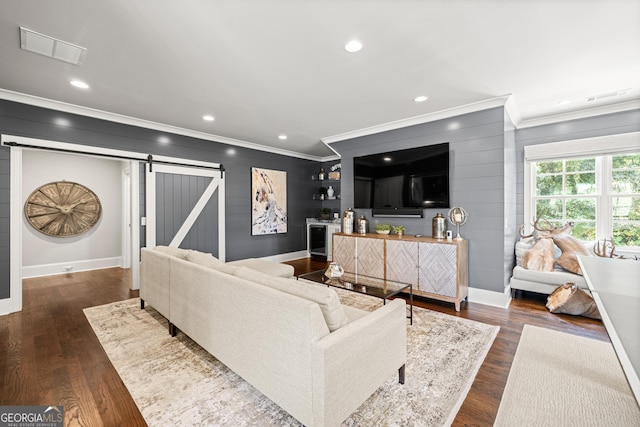 living room with crown molding, dark wood-type flooring, and a barn door