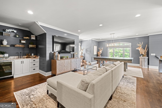 living area featuring dark wood-type flooring, wine cooler, ornamental molding, and wet bar