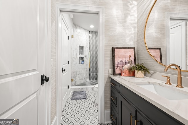 bathroom featuring tile patterned flooring, vanity, a tile shower, and toilet