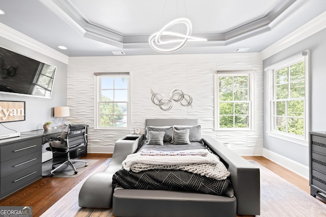 bedroom with baseboards, ornamental molding, a raised ceiling, and wood finished floors