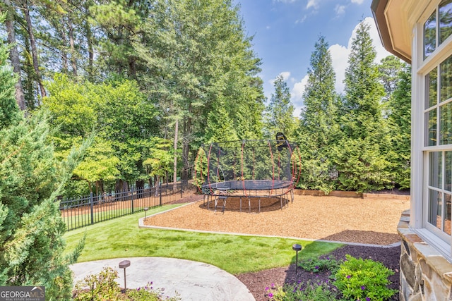 view of yard featuring a trampoline and fence