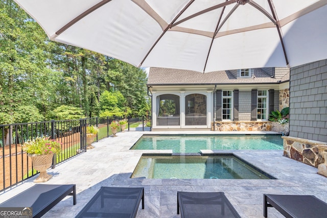 view of swimming pool with a patio area, fence, and a pool with connected hot tub