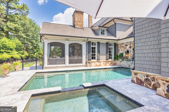 view of swimming pool featuring a pool with connected hot tub, a patio area, and fence