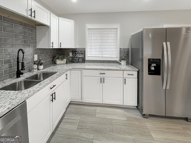 kitchen with white cabinetry, appliances with stainless steel finishes, sink, and light stone counters