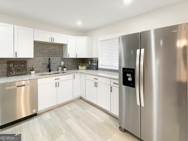 kitchen featuring sink, light stone countertops, white cabinets, and appliances with stainless steel finishes