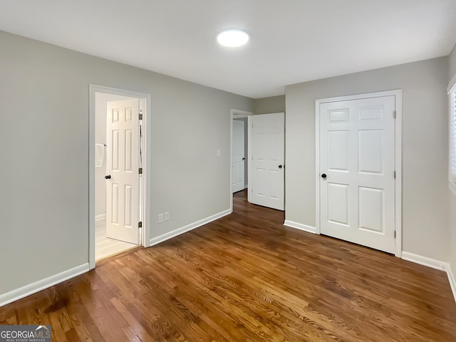 unfurnished bedroom featuring dark hardwood / wood-style floors and connected bathroom