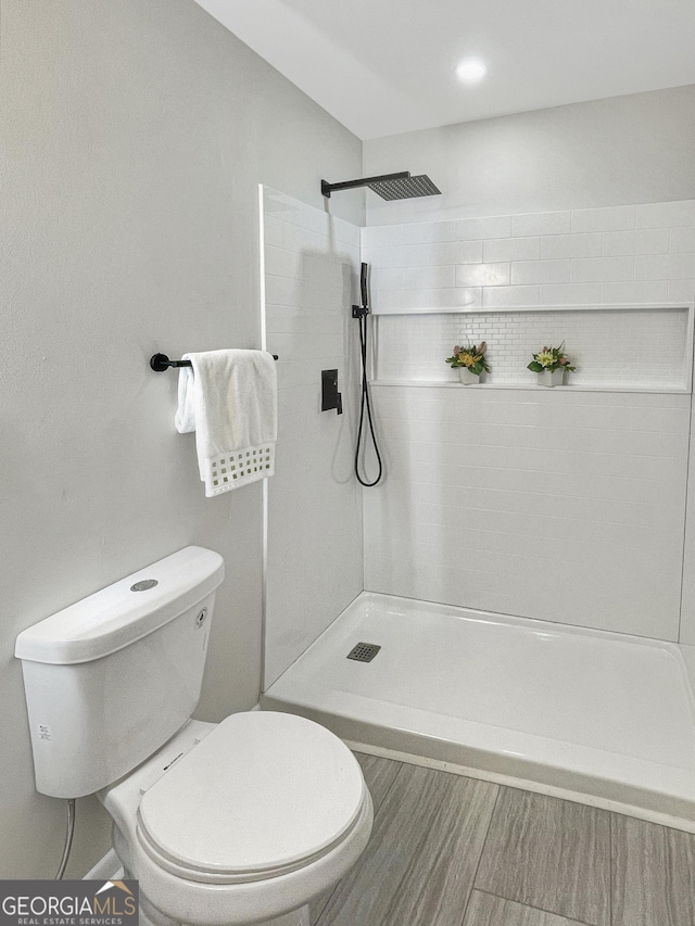 bathroom featuring tiled shower and toilet