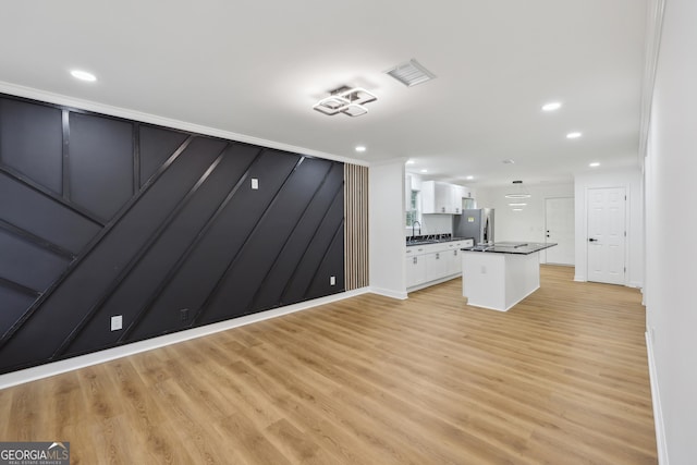 unfurnished living room featuring light wood-style flooring, visible vents, a sink, and recessed lighting