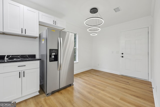 kitchen featuring stainless steel refrigerator with ice dispenser, dark countertops, visible vents, white cabinets, and light wood-type flooring