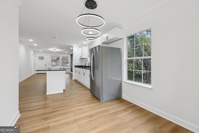 kitchen with light wood-style flooring, freestanding refrigerator, white cabinets, and dark countertops