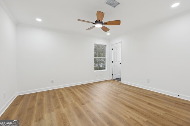 spare room with baseboards, light wood-type flooring, visible vents, and crown molding