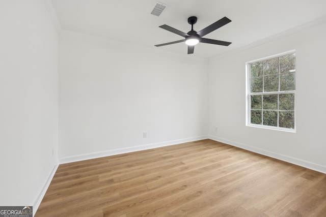 spare room with light wood finished floors, baseboards, visible vents, and ornamental molding