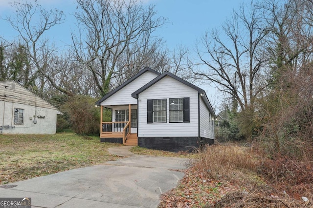 bungalow-style home featuring covered porch, a front lawn, and crawl space