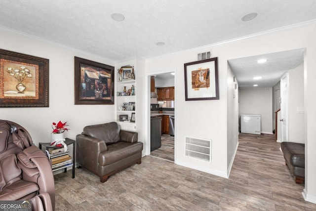 living area featuring hardwood / wood-style flooring, ornamental molding, and a textured ceiling