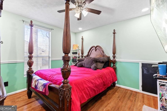 bedroom featuring ceiling fan, hardwood / wood-style floors, and a textured ceiling