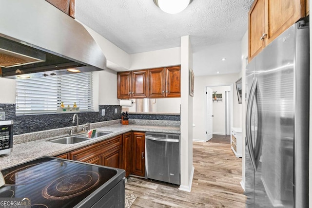 kitchen with sink, stainless steel appliances, extractor fan, a textured ceiling, and light wood-type flooring