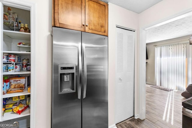 kitchen with hardwood / wood-style floors, a textured ceiling, and stainless steel refrigerator with ice dispenser