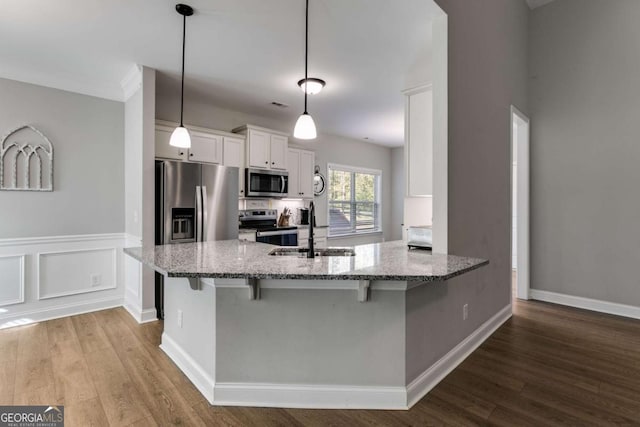 kitchen featuring sink, light stone counters, hanging light fixtures, appliances with stainless steel finishes, and white cabinets