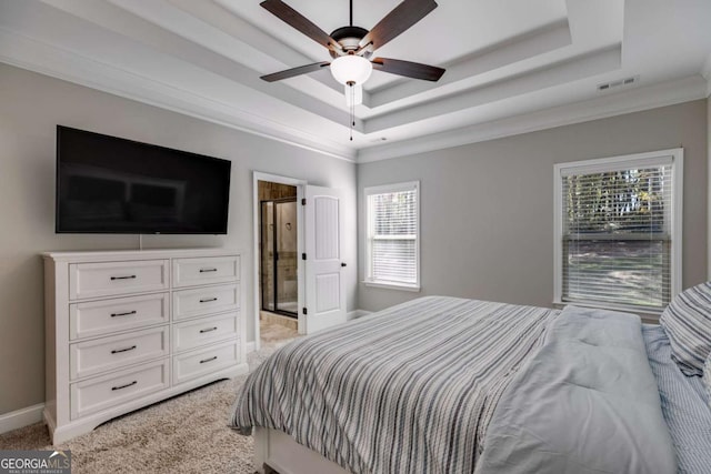 carpeted bedroom with a tray ceiling, ensuite bath, and ceiling fan