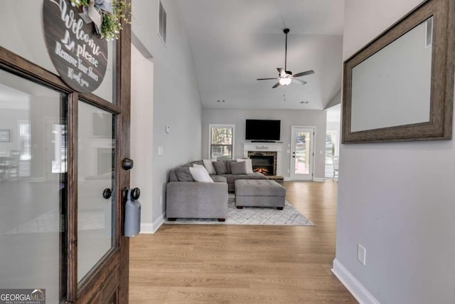 living room featuring ceiling fan, high vaulted ceiling, and light hardwood / wood-style floors