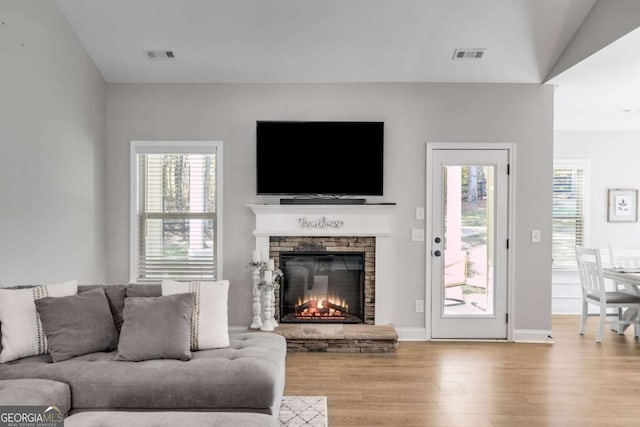 living room featuring a stone fireplace and light hardwood / wood-style floors