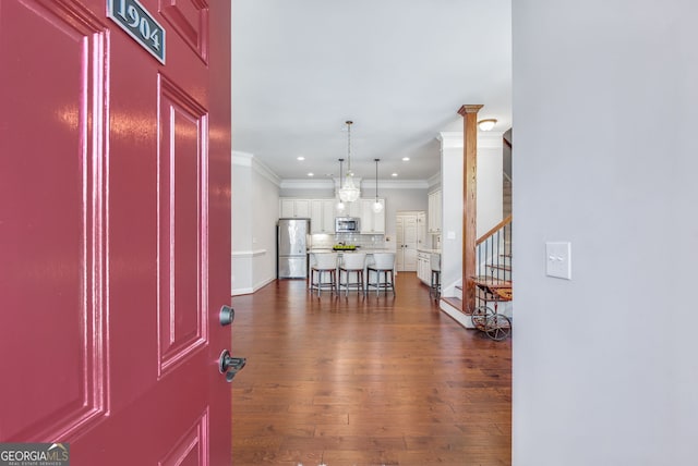 entrance foyer with dark hardwood / wood-style flooring and crown molding