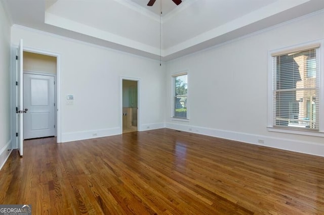 unfurnished room featuring ceiling fan, ornamental molding, dark hardwood / wood-style floors, and a tray ceiling