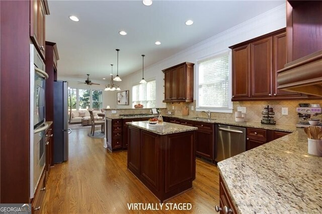 kitchen featuring pendant lighting, stainless steel appliances, kitchen peninsula, and light stone countertops