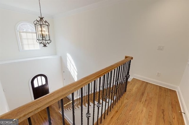 interior space with ornamental molding, wood-type flooring, and a notable chandelier