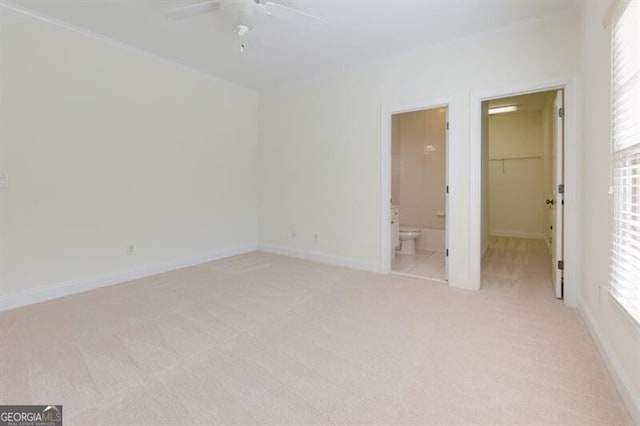 unfurnished bedroom featuring connected bathroom, a spacious closet, ceiling fan, light carpet, and a closet