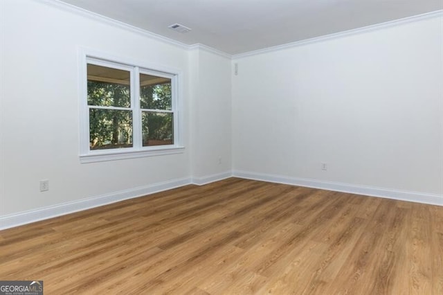 empty room featuring ornamental molding and light wood-type flooring