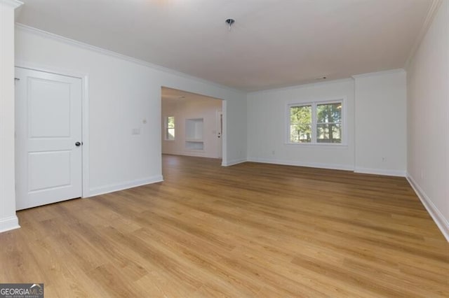 empty room featuring crown molding, a wealth of natural light, and light wood-type flooring