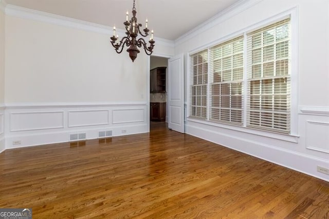 unfurnished dining area featuring a notable chandelier, crown molding, and dark hardwood / wood-style floors