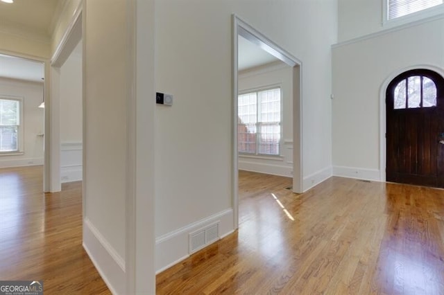 foyer entrance with ornamental molding and light wood-type flooring