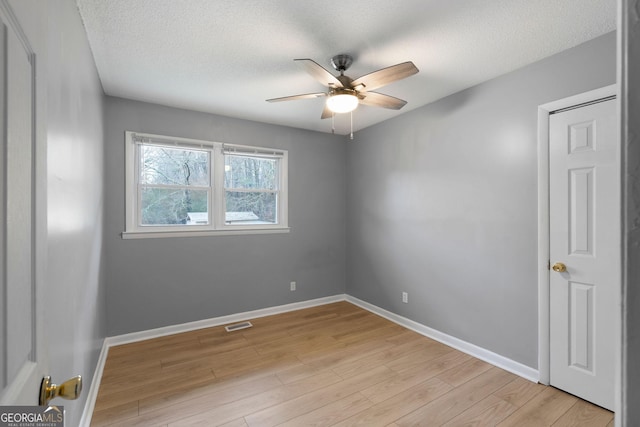 empty room featuring ceiling fan, a textured ceiling, and light hardwood / wood-style floors