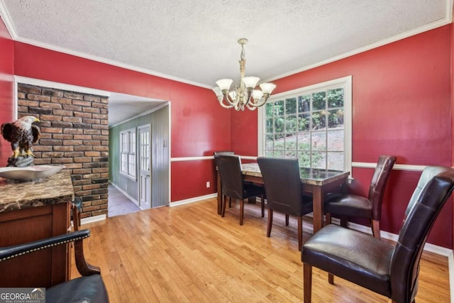 dining area featuring crown molding, a chandelier, and light hardwood / wood-style flooring