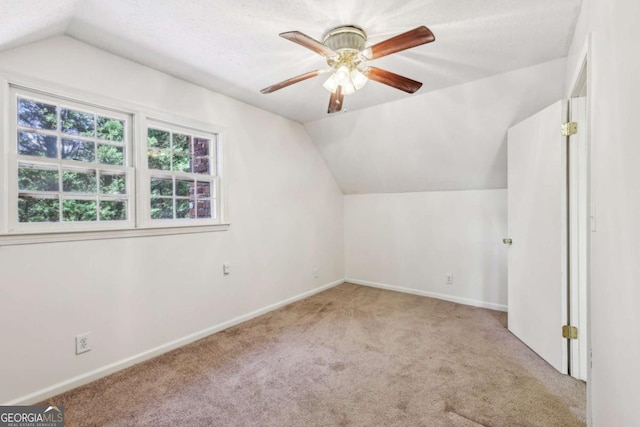 additional living space featuring ceiling fan, lofted ceiling, carpet floors, and a textured ceiling