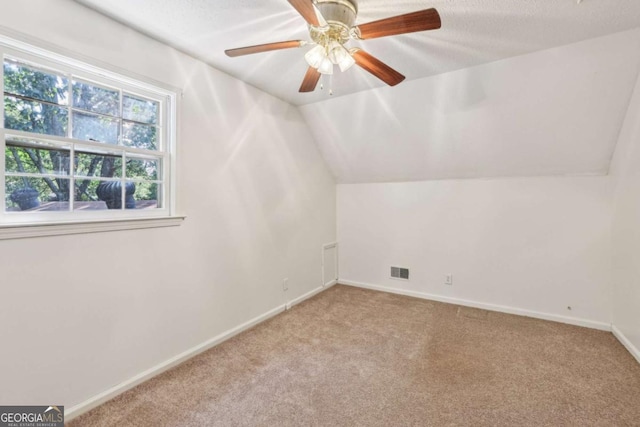 additional living space with light carpet, a textured ceiling, lofted ceiling, and ceiling fan