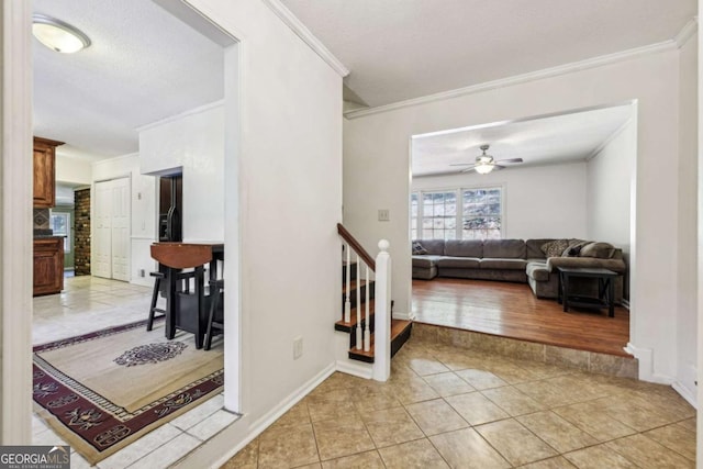 interior space featuring ceiling fan, tile patterned floors, ornamental molding, and a textured ceiling