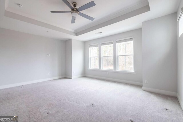 carpeted empty room featuring a raised ceiling and ceiling fan