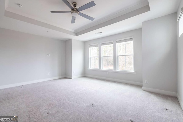 unfurnished room featuring light colored carpet, a raised ceiling, visible vents, and baseboards