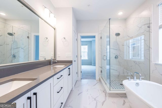 bathroom featuring marble finish floor, a marble finish shower, double vanity, a freestanding bath, and a sink