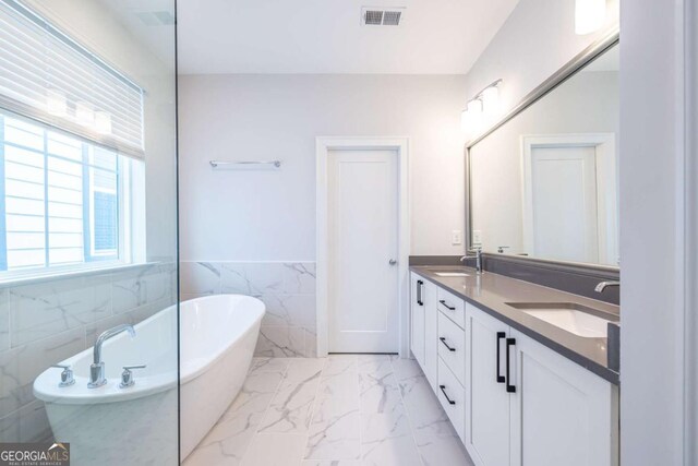 bathroom with a bathing tub, tile walls, and vanity