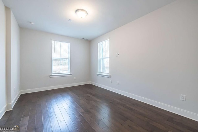 unfurnished room with baseboards and dark wood-type flooring