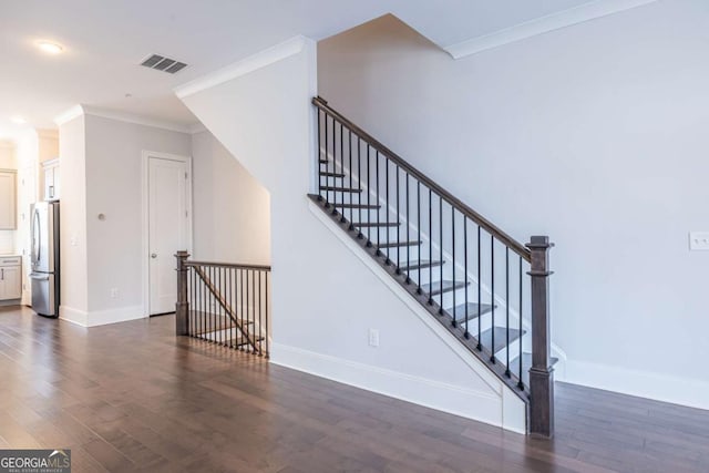 staircase with wood-type flooring and ornamental molding